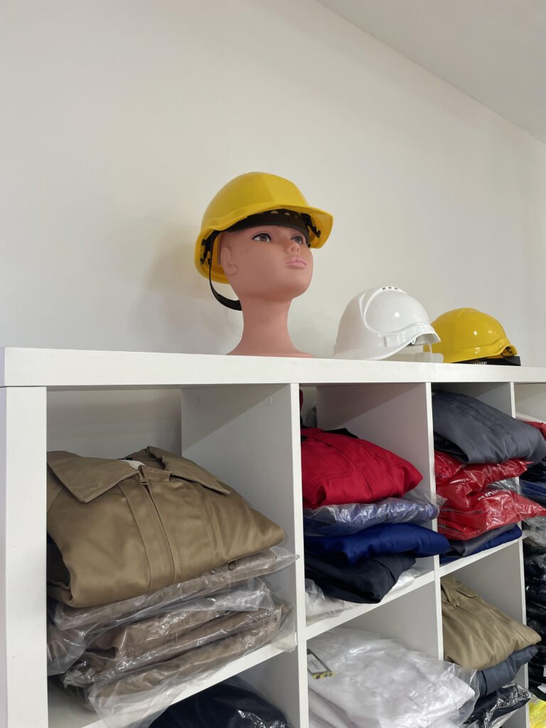 Estantería con cascos de protección y prendas de trabajo dobladas